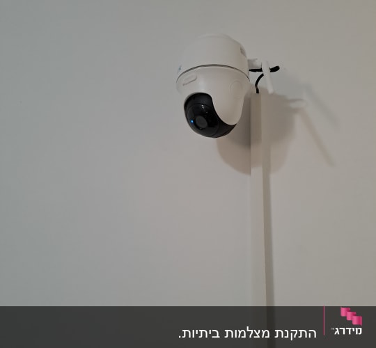 מצלמת אבטחה לבנה מותקנת על קיר